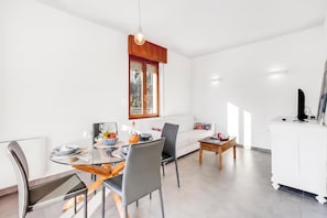 Een eetgedeelte met een tafel voor twee personen, een witte bank en een bijzettafeltje met een kaars.