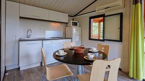 Une cuisine moderne avec des meubles blancs, un four à micro-ondes et un réfrigérateur. On y trouve une table à manger avec des chaises et un panier.