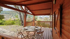 Une terrasse en bois avec une table et des chaises, offrant une vue sur un paysage montagneux.