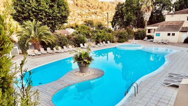 Une piscine avec une terrasse en bois et des chaises longues.