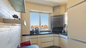 Een kleine keuken met een raam, een inbouwoven en een koelkast.