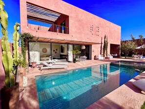 A modern house with a swimming pool, outdoor furniture, and potted plants. - Palais Celeste (Marrakech)