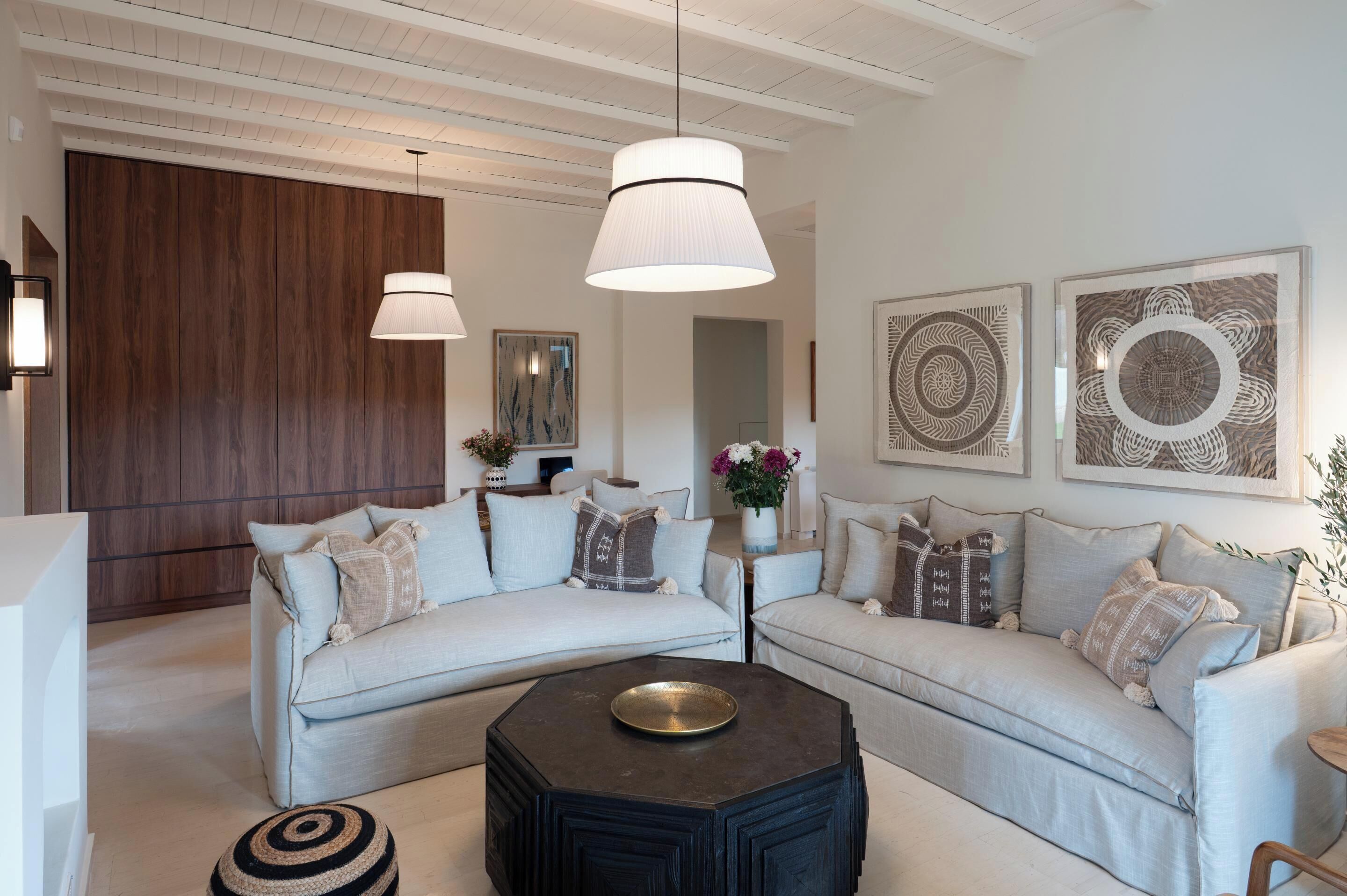 A modern living room with two light-colored sofas, a black coffee table, and decorative wall art.