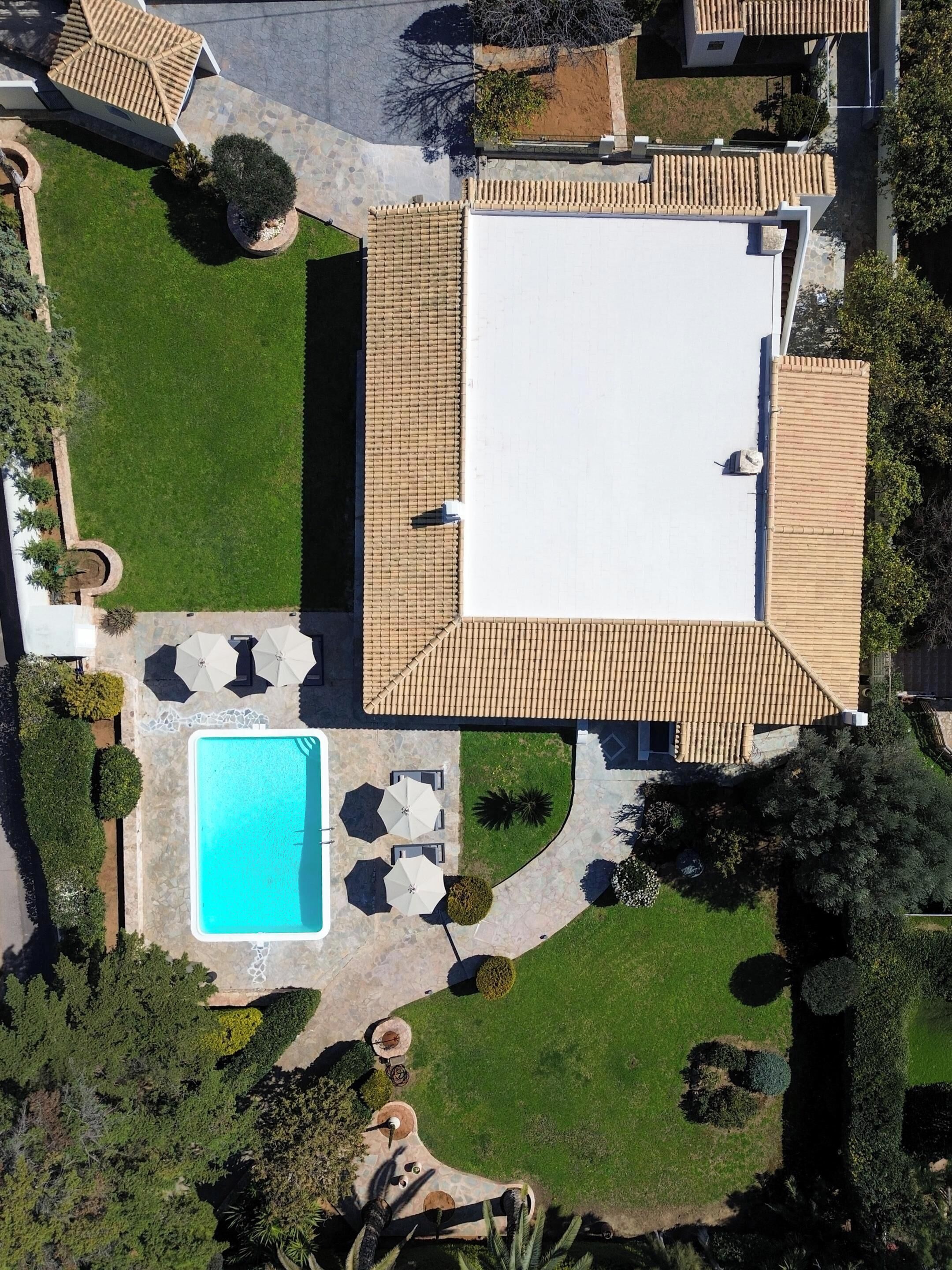 Vista aérea de una propiedad con piscina, mobiliario exterior y un césped bien cuidado.
