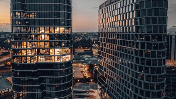 A modern high-rise building with a curved facade, large windows, and a parking area in front. - Apartament Bulvar - by Kairos Apartments (Katowice)