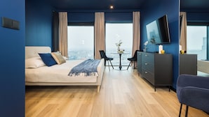 A modern bedroom with a bed, a desk, and a TV. - Apartament Bulvar - by Kairos Apartments (Katowice)