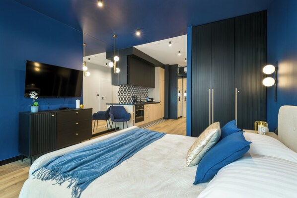 Un dormitorio moderno con una cama grande, un escritorio y un televisor.