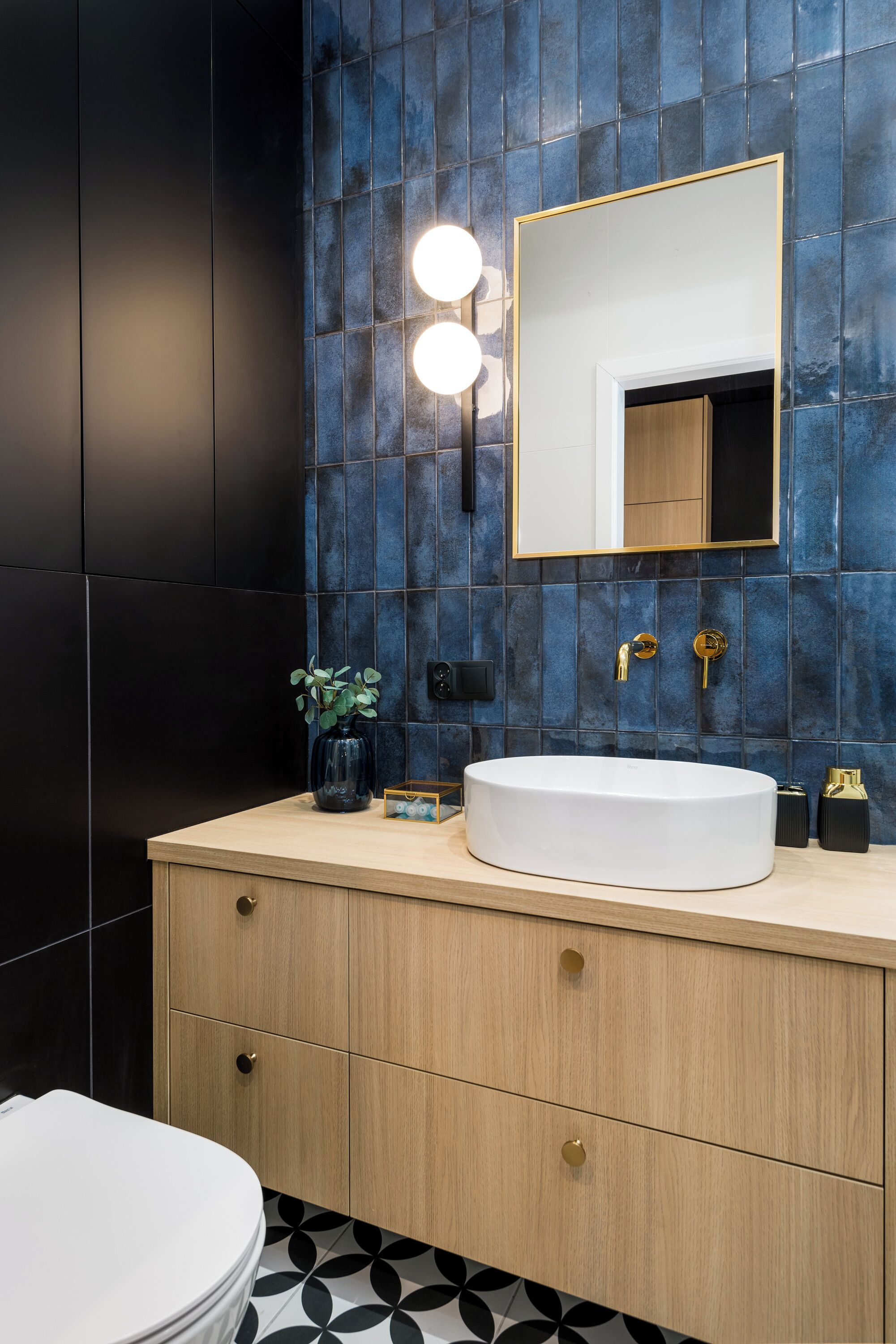 Un bagno moderno con un grande specchio, un lavandino bianco e un mobile vanitario in legno.