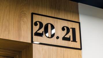 Een houten muur met een zwart omlijst bord waarop de cijfers '20.21' staan.