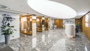 A modern reception area with a marble floor, wooden accents, and a large illuminated ceiling feature. - Apartament Bulvar - by Kairos Apartments (Katowice)