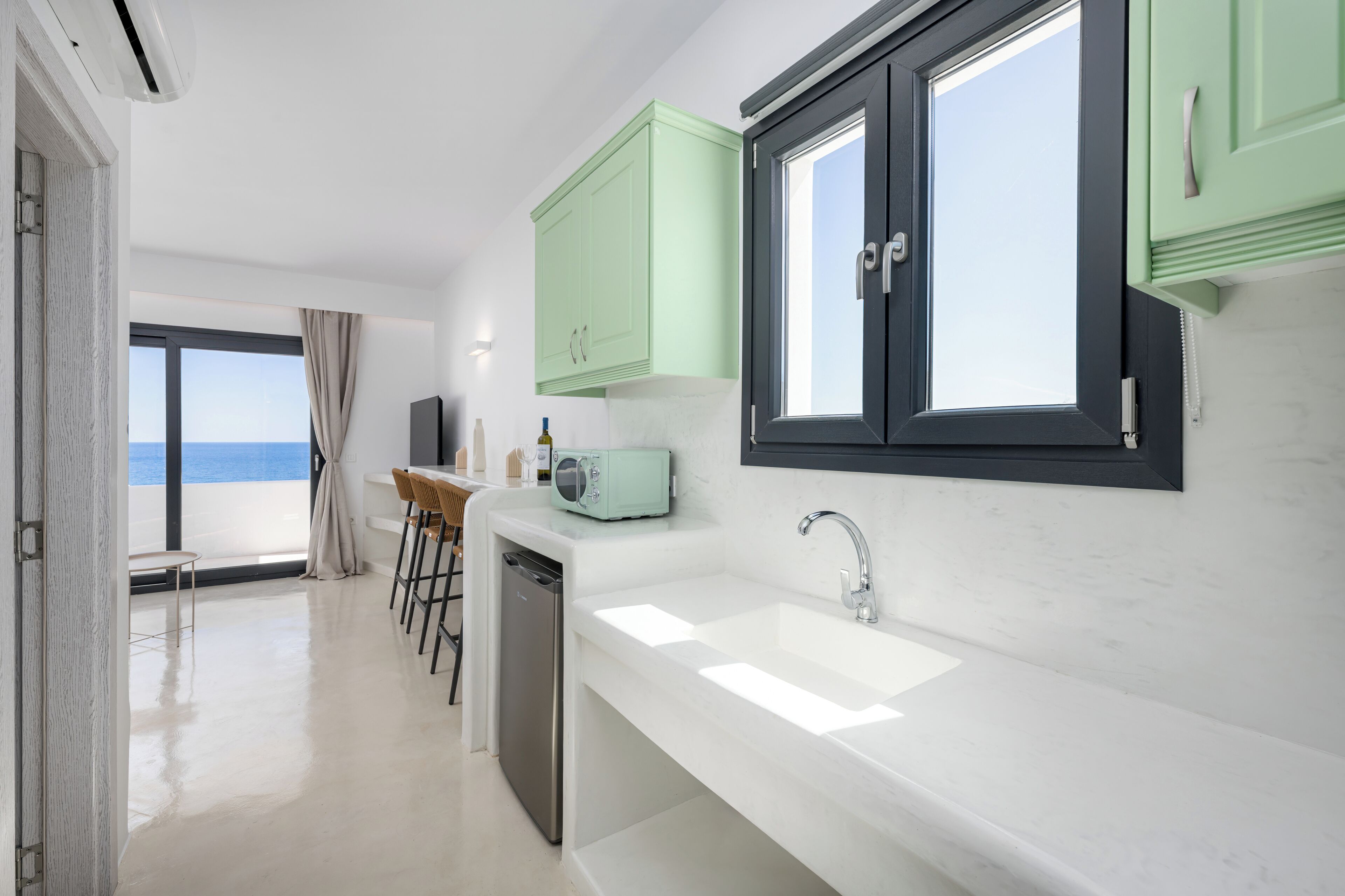 Una cocina moderna con encimera blanca, lavavajillas integrado y ventana con vistas al mar.