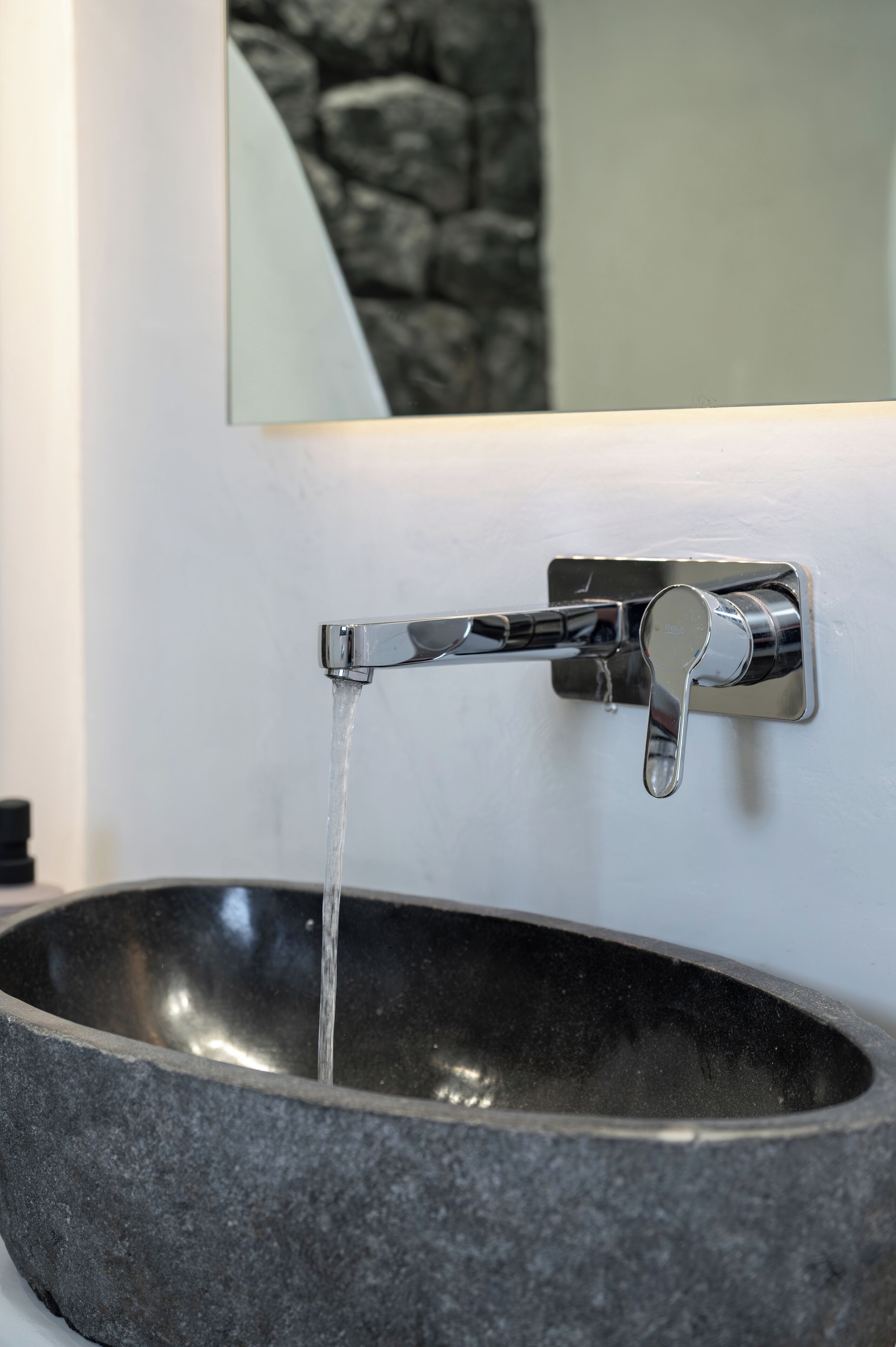 A modern bathroom with a stone basin and a chrome faucet.