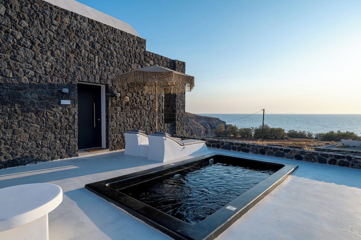 Un bâtiment en pierre doté d’une piscine et offrant une vue sur la mer.