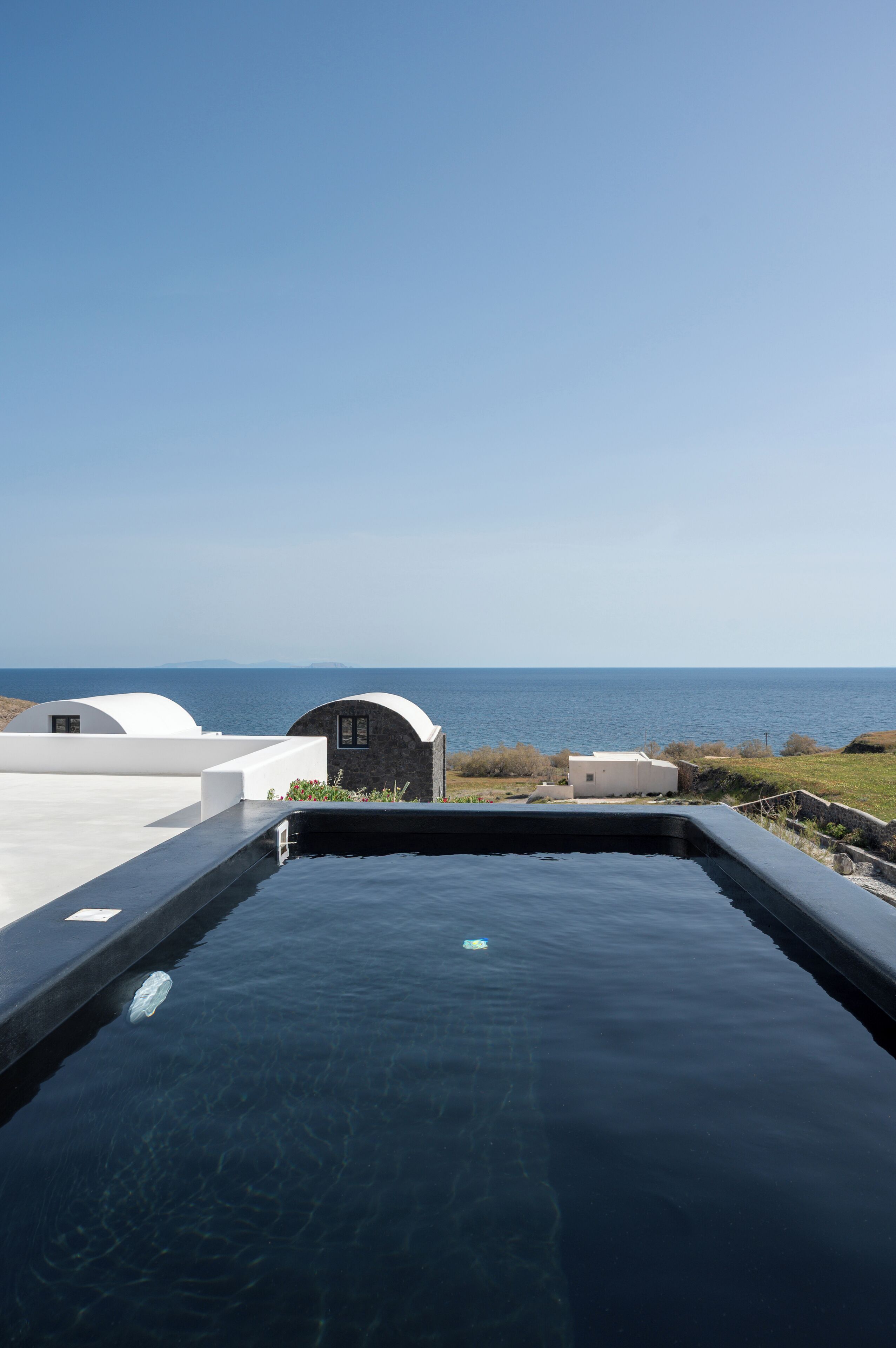 A swimming pool with a view of the sea and a building with a curved roof.