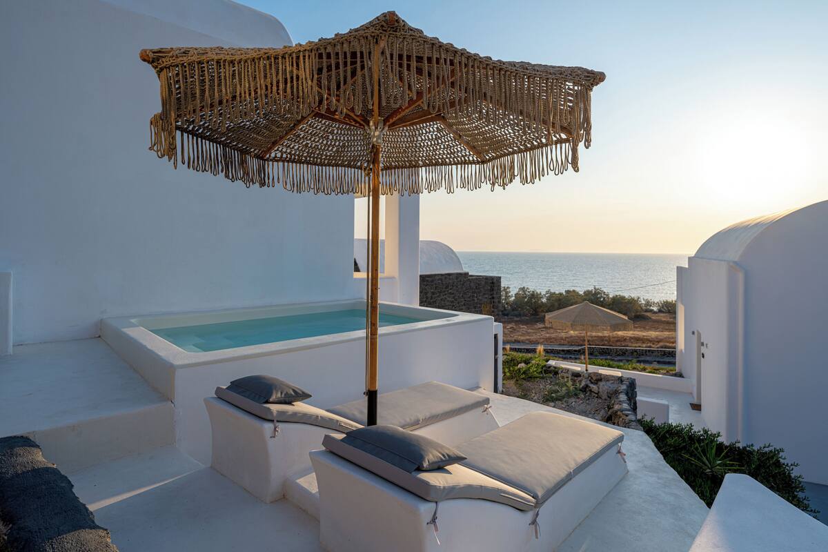 Une terrasse sur le toit équipée d’un jacuzzi, de chaises longues et d’un parasol en osier.