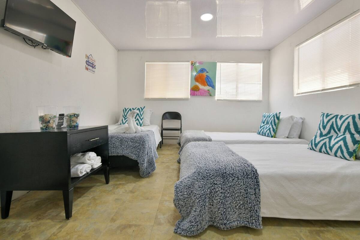 A hotel room with two beds, a desk, a chair, and a TV.