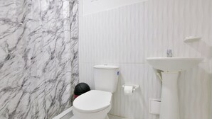 A bathroom with a toilet, sink, and marble wall.