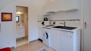 Ett kompakt kök med tvättmaskin, mikrovågsugn och diskho.