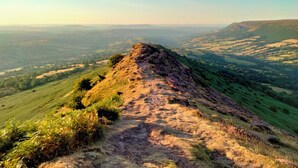 A panoramic view of a hilly landscape with a clear path leading to a peak.
