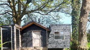 A small wooden cabin with a front door, a window, and a small porch area.
