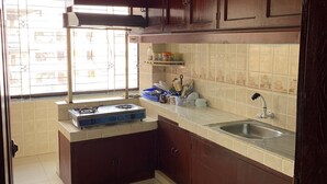 Una cocina con armarios de madera oscura, una estufa a gas, un lavamanos y una ventana con vistas a edificios.