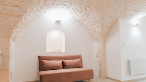 Une pièce avec un plafond en pierre, un mur blanc et un canapé marron.