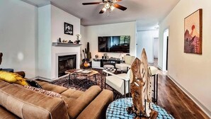 A living room with a brown sofa, a patterned rug, a blue round table, and a fireplace.