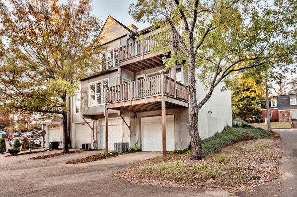 A two-story house with a balcony, garage, and a tree in front.