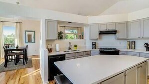A modern kitchen with white cabinetry, a central island, and a dining area with a table and chairs.