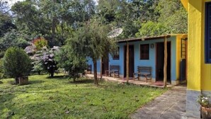 A house with a porch, a satellite dish, and a small garden with trees and shrubs. - Recanto Mineiro (São Lourenço)