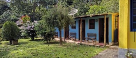 A house with a porch, a satellite dish, and a small garden with trees and shrubs.