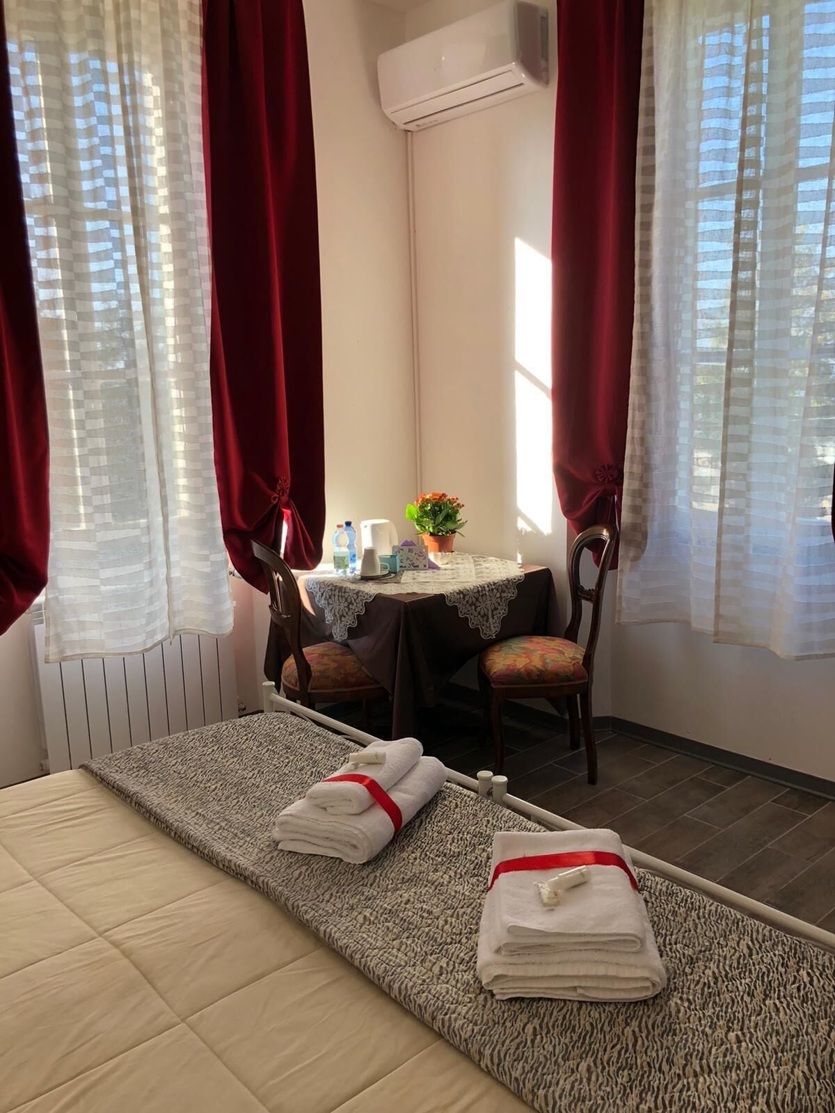 A hotel room with a bed, a small table with chairs, and a potted plant.