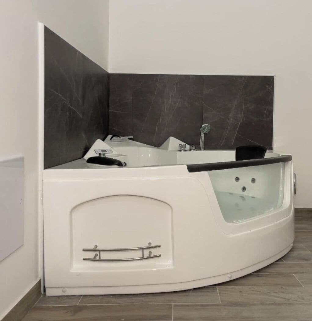 A corner bathroom with a freestanding bathtub, a shower, and a vanity with a mirror.