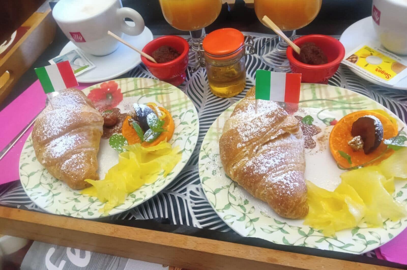 A tray with two plates of food, each with a flag, a cup, and a jar of honey.