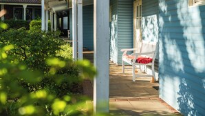 A porch with a bench, a covered area, and a house with blue siding. - Zur Rennbahn (Drage)