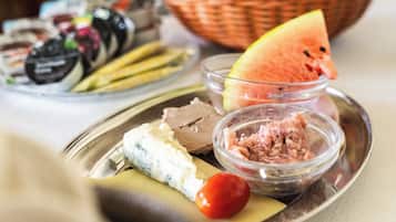 Ein Teller mit verschiedenen Speisen, darunter Käse, eine Tomate und eine Schüssel mit Fleisch.