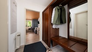 A hallway with a wooden bench, a coat rack with jackets, and a radiator. - Zur Rennbahn (Drage)