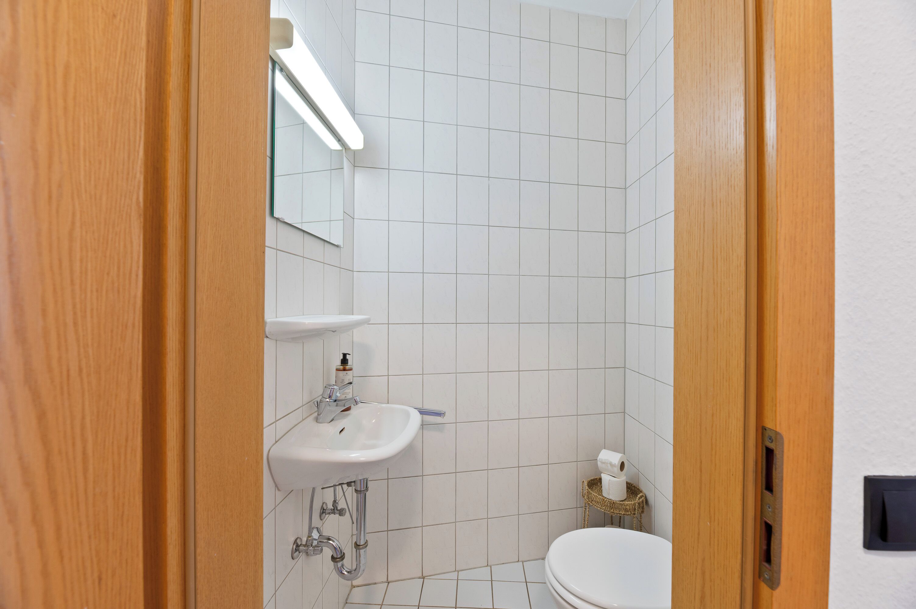 A bathroom with a white sink, mirror, and toilet.