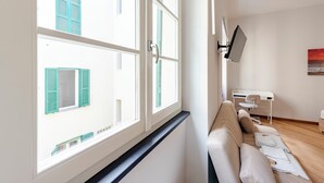 Een kamer met een bank, een bureau en een aan de muur bevestigde televisie.