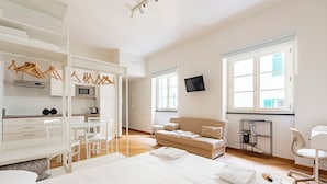Een moderne hotelkamer met een bed, een bank, een bureau met een stoel, een televisie en een kledingkast.