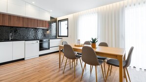 A modern kitchen with white cabinets, a black backsplash, and wooden flooring.