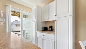 A kitchen with white cabinets, a granite countertop, and a coffee maker. - Siesta Villa 104s (Ocean City)