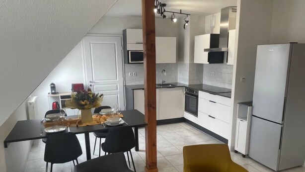 A modern kitchen with white cabinets, a built-in microwave, and a stainless steel refrigerator. - Le square Spacious apartment with terrace & garage, quiet location near Colmar  (Sundhoffen)