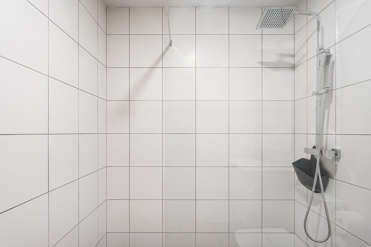 A modern shower with a handheld showerhead and a wall-mounted faucet.