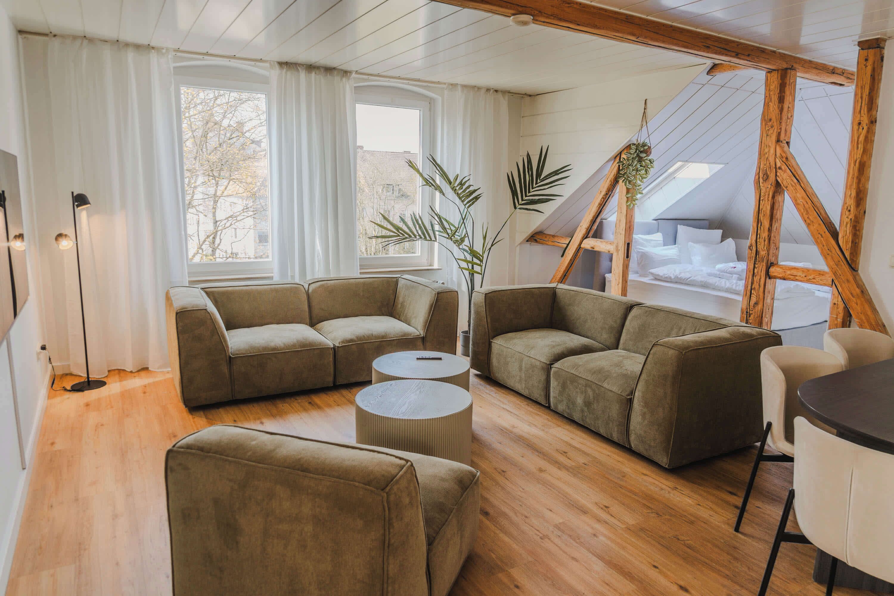 A cozy living room with a sectional sofa, two round coffee tables, and a wooden ceiling.