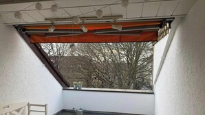 A corner room with a sloped ceiling, a bench, a window with a view of trees and buildings, and a small potted plant on the windowsill. - Penthouse in Hildesheims Philosophen Viertel (Hildesheim)