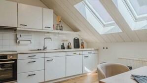 A modern kitchen with white cabinets, a built-in oven, and a skylight. - Penthouse in Hildesheims Philosophen Viertel (Hildesheim)