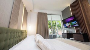 A hotel room with a large bed, a TV on a wooden stand, and a window with curtains. - H106 - Amazing Comfort & Amenities, Pool, Security (Cali)