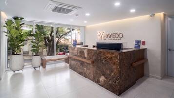 A reception desk with a marble top, a sign reading 'YHayedo de Juanambú,' and potted plants.