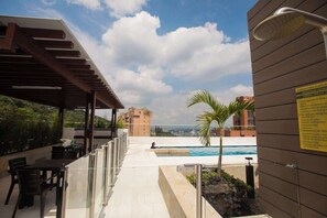 A rooftop pool area with a covered seating area, a view of the city, and a sign with information. - H309 - Gorgeous 1BR | Balcony | Pool | Parking (Cali)